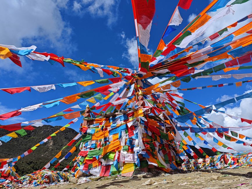 Prayer flags strung between wooden poles at Chele La Pass fluttering in strong mountain wind