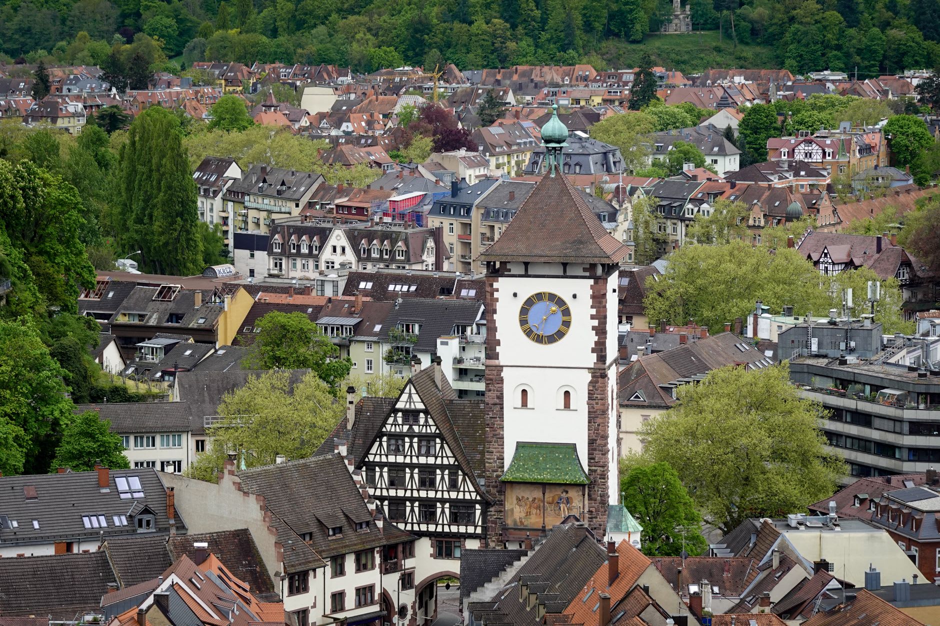 The red sandstone Münster cathedral towering above morning market stalls, its single Gothic spire framed by clear sky