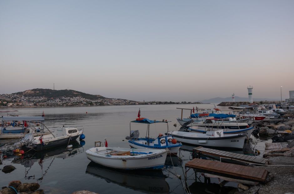 Fishing boats moored in Amasra's harbor at sunset with the old town behind