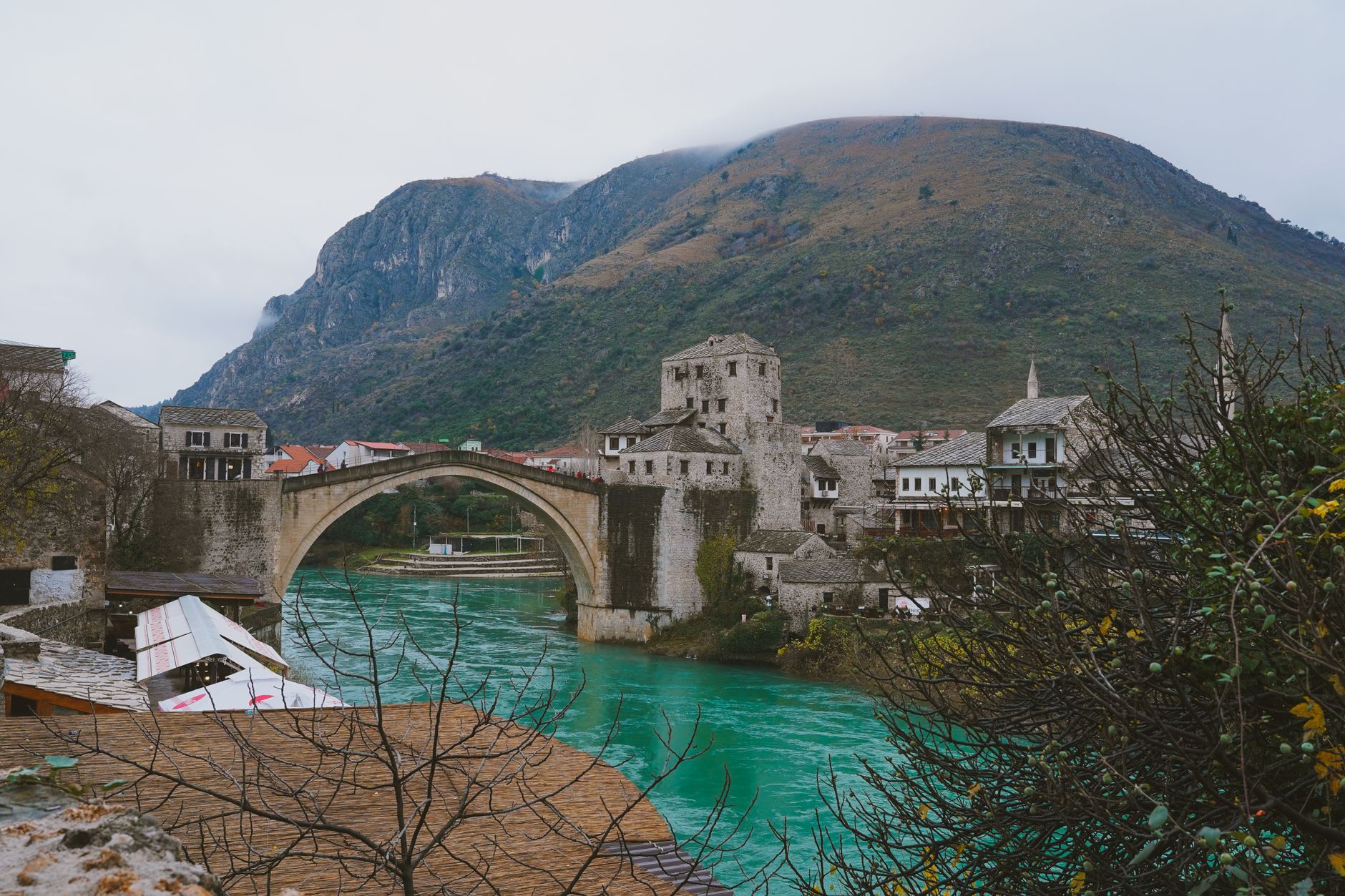 A diver launching from the parapet of Stari Most into the cold Neretva below on a summer afternoon