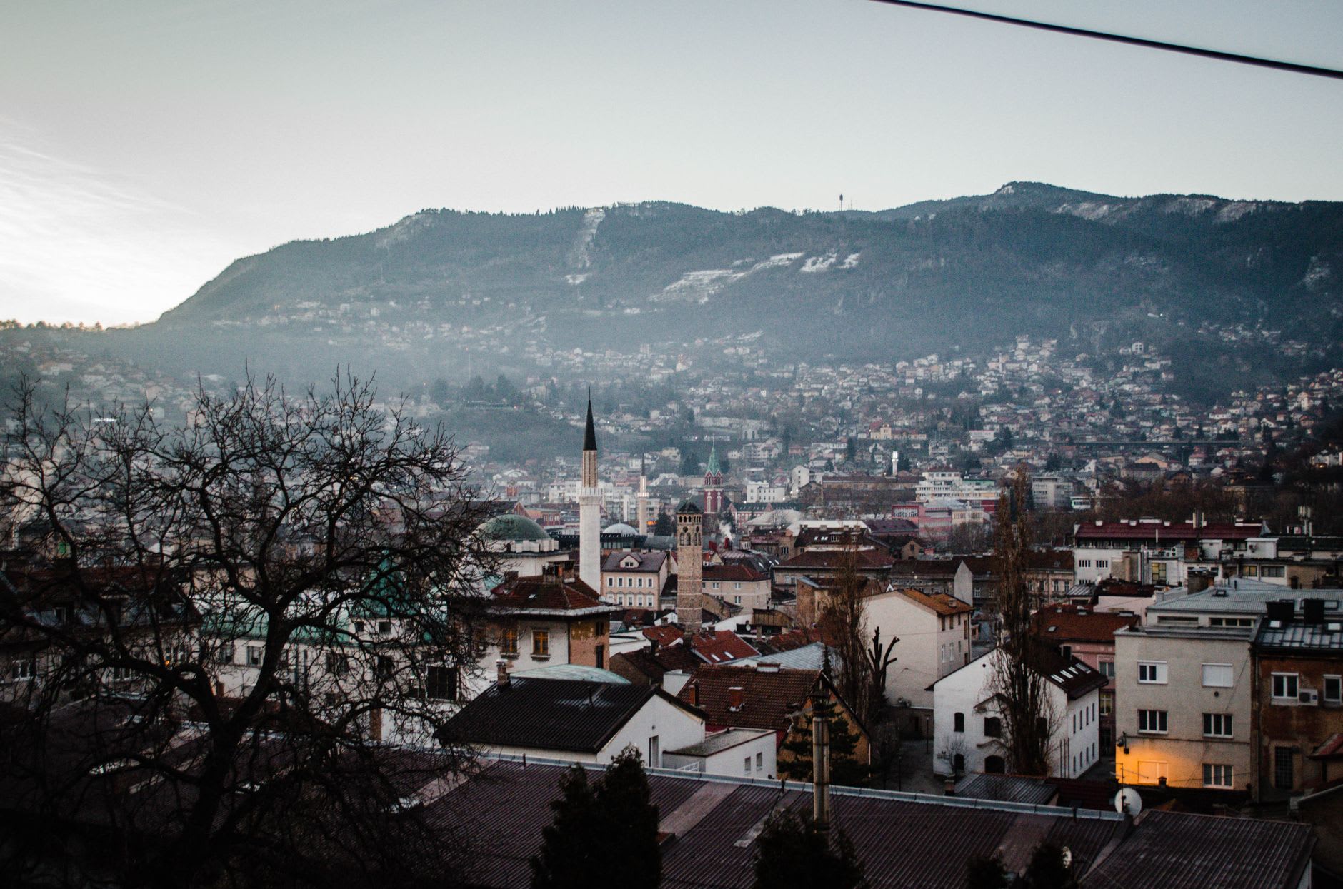 Travnik's medieval fortress walls seen from below, the town and the Lašva valley spreading behind