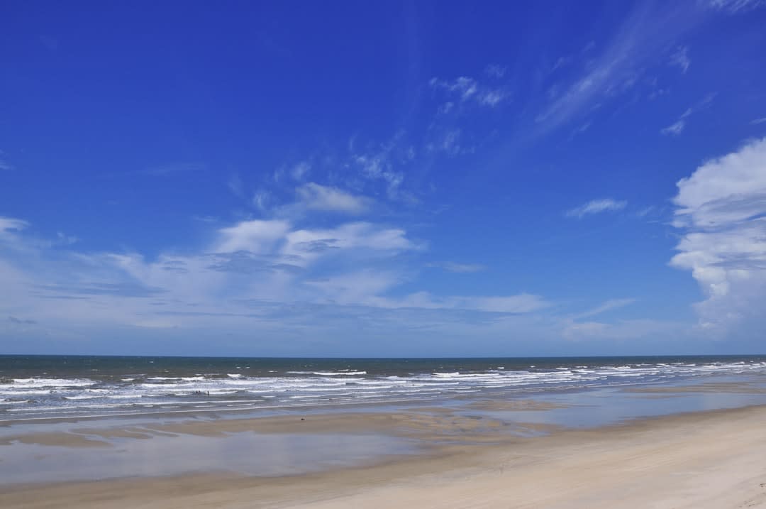 A dune buggy crossing sand tracks on the outskirts of Barreirinhas with the town visible in the distance