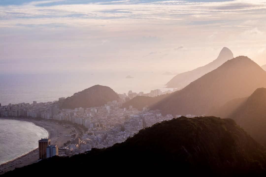 Crowds gathered on the rocks of Arpoador at sunset, silhouetted against the orange sky