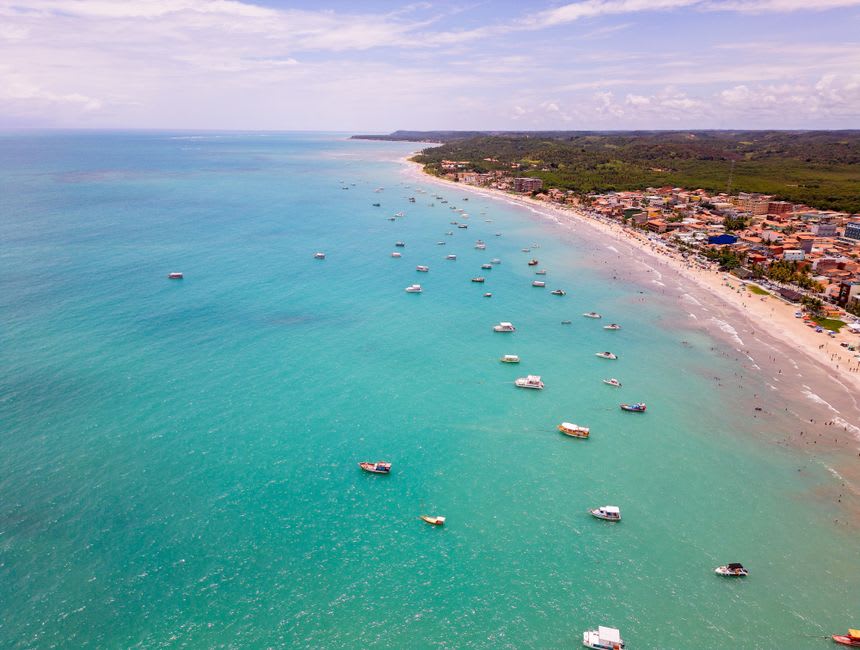 A catamaran full of passengers anchored over the turquoise Piscinas de Galés reef pools off Maragogi, the water impossibly clear