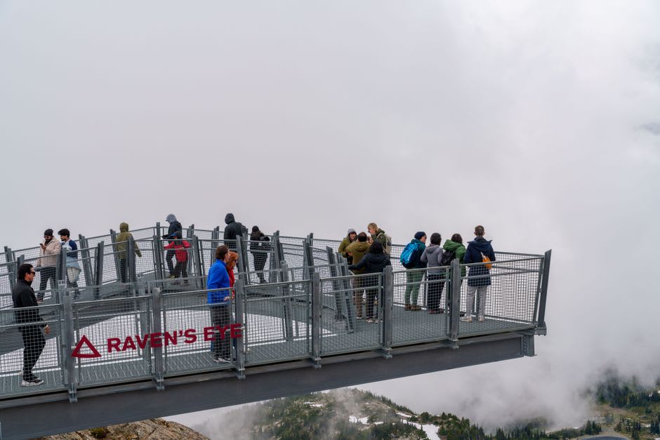 The glass-floored skywalk at Kicking Horse Mountain Resort cantilevered over the Columbia Valley with paragliders in the sky