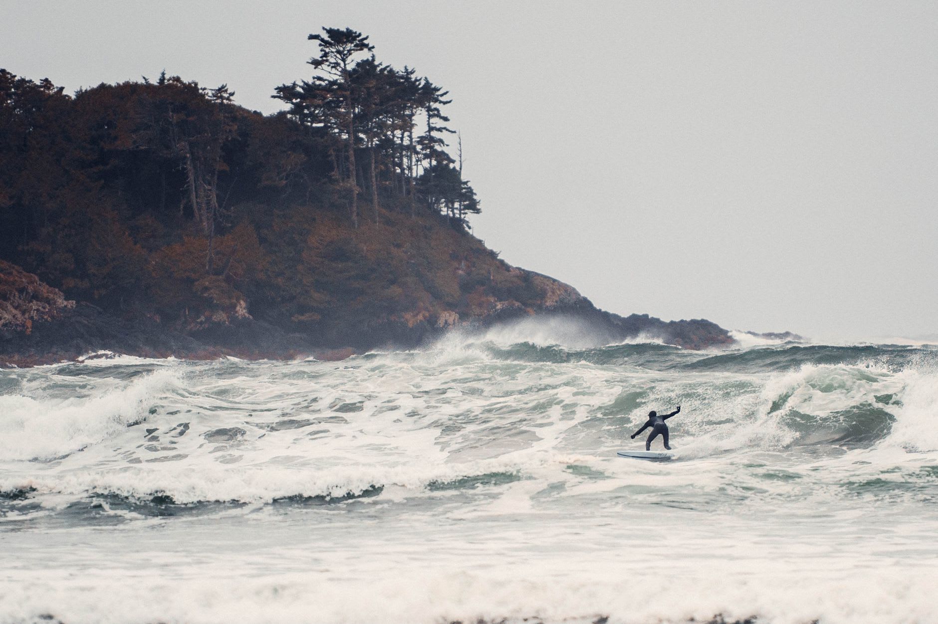 Surfistas al atardecer en Chesterman Beach en Tofino, el cielo volviéndose naranja sobre un swell oscuro del Pacífico