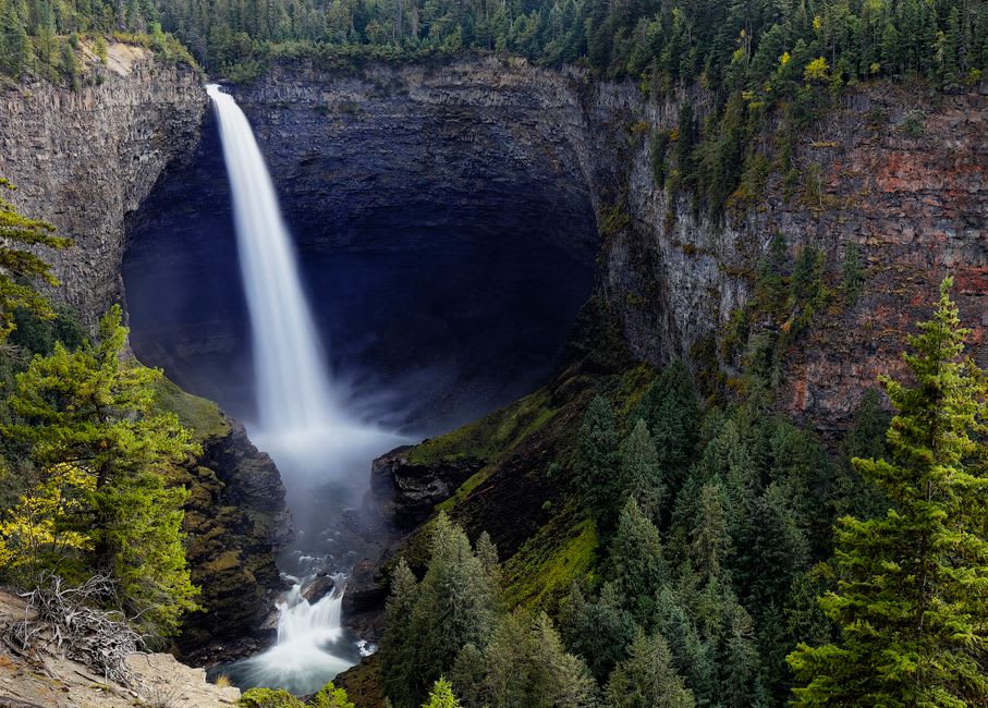 Les chutes Helmcken tombant d'une falaise de basalte dans un canyon rempli de brume, encadrées par une forêt dense de conifères
