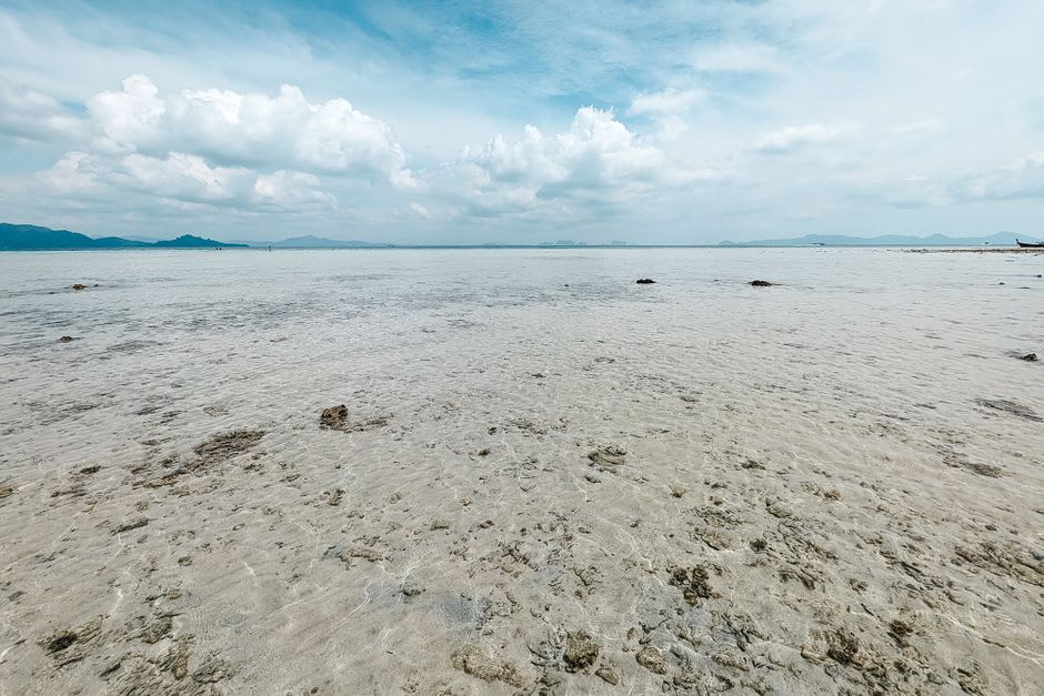 Shallow turquoise water at Smuggler's Cove with pale sand and Jost Van Dyke visible in the distance across the channel