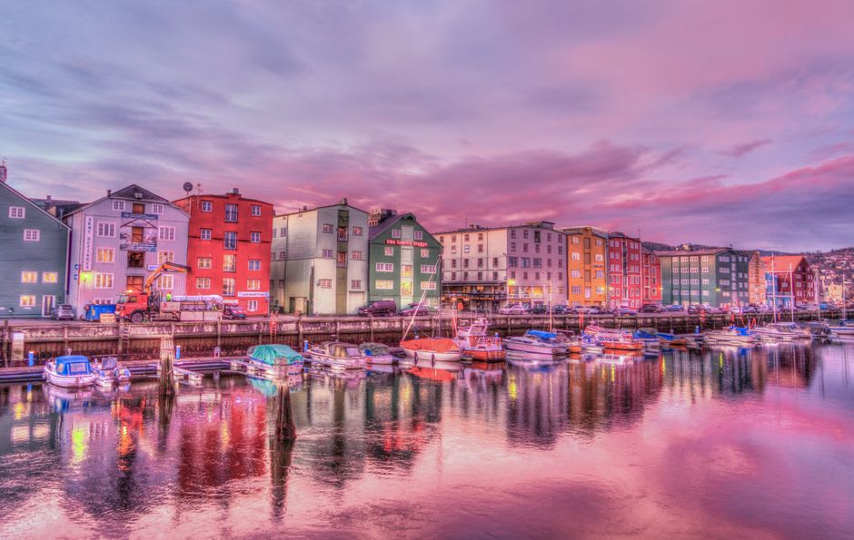 Colorful gingerbread-trimmed buildings lining the waterfront at Soper's Hole marina with boats moored along the dock