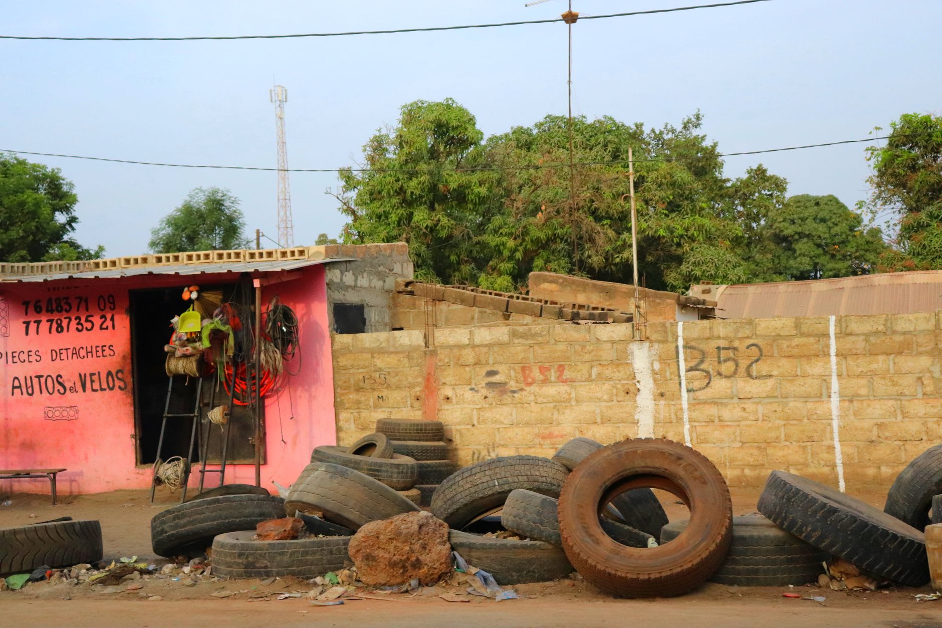 The Banfora central market in morning activity, women selling smoked fish over braziers while buyers carry baskets of grain and produce through the narrow aisles