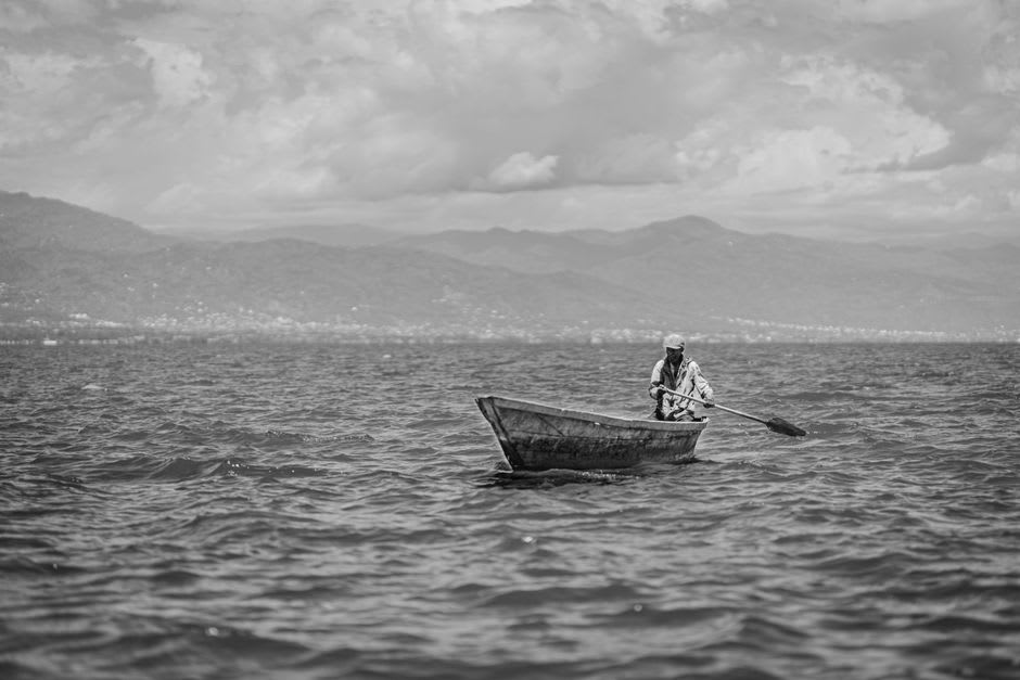 Wooden pirogue fishing boats pulled up on the sand near Saga Beach with fishermen sorting the morning catch