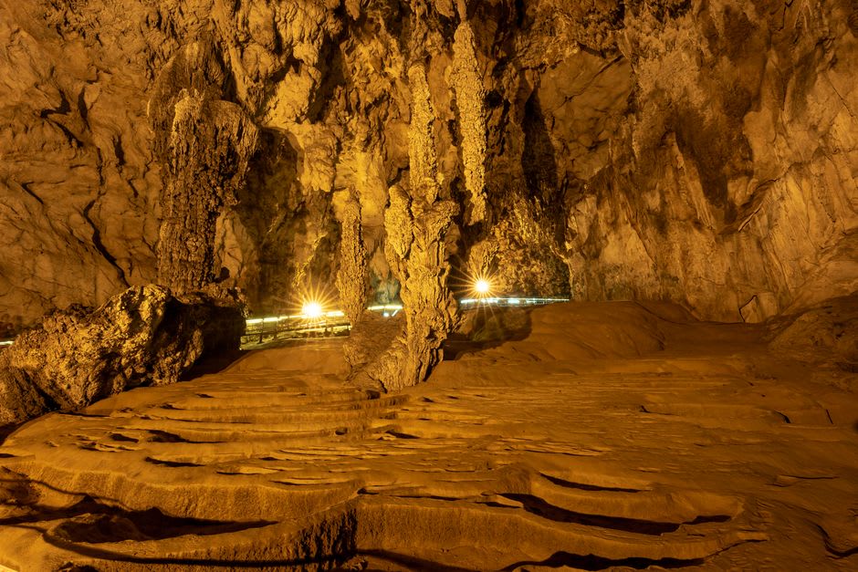 Illuminated limestone chamber inside Gruta de Ubajara showing stalactite and stalagmite formations along the walkway