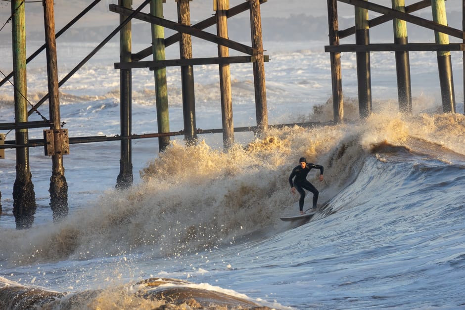 Surfer riding the tidal bore wave upstream on the Petitcodiac River near Moncton