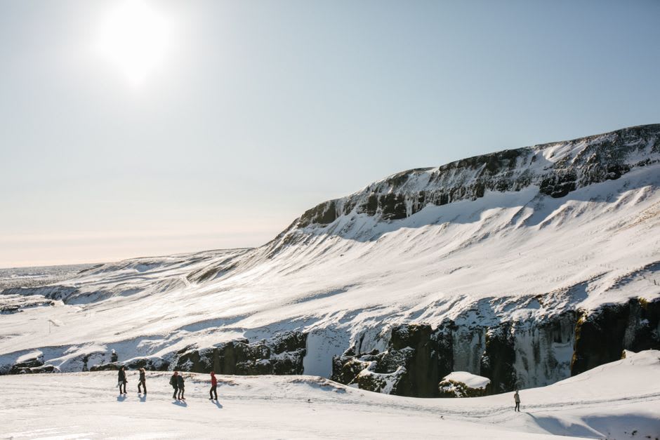 Tourists walking on the blue-white ice of the Athabasca Glacier beside a massive Ice Explorer vehicle