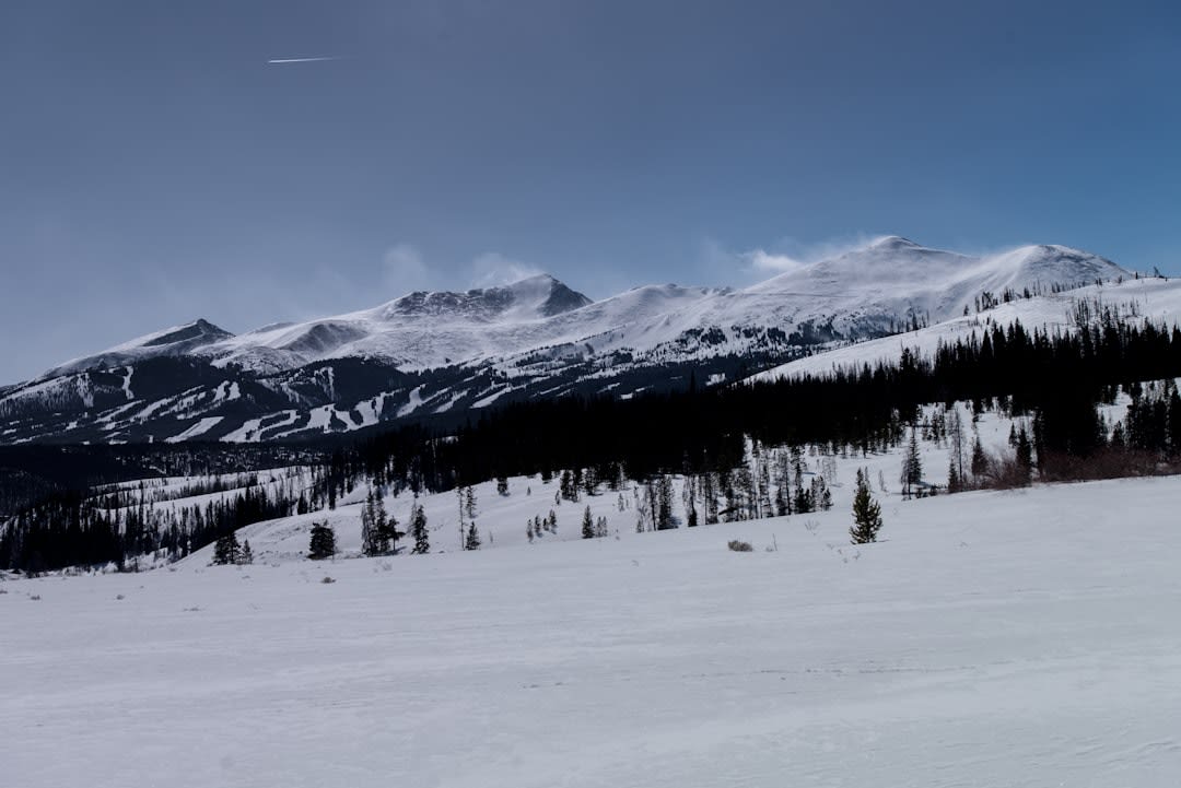 Skiers descending a deep powder bowl surrounded by jagged limestone peaks