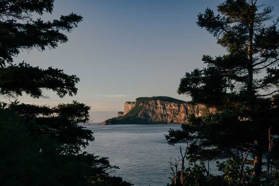 Hiker on cliffside trail at Forillon National Park with the Gulf of St. Lawrence beyond