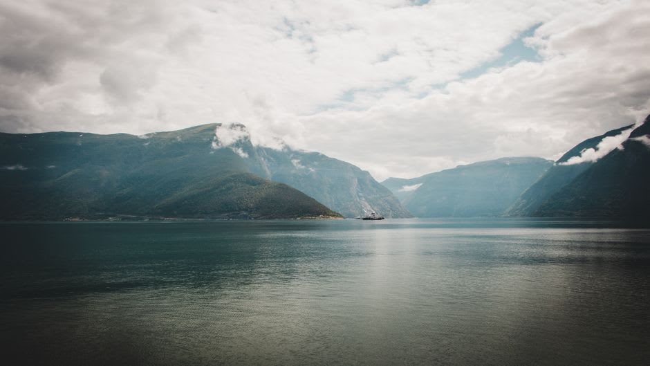 A tour boat gliding through Western Brook Pond between towering cliff walls