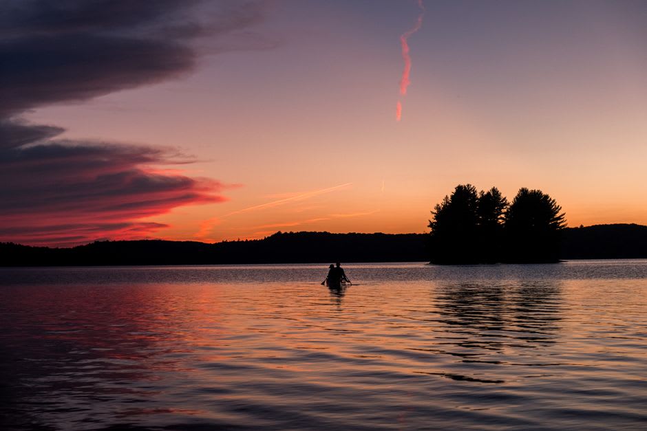 Kayak gliding across still water at dusk near a forested Gulf Island shoreline