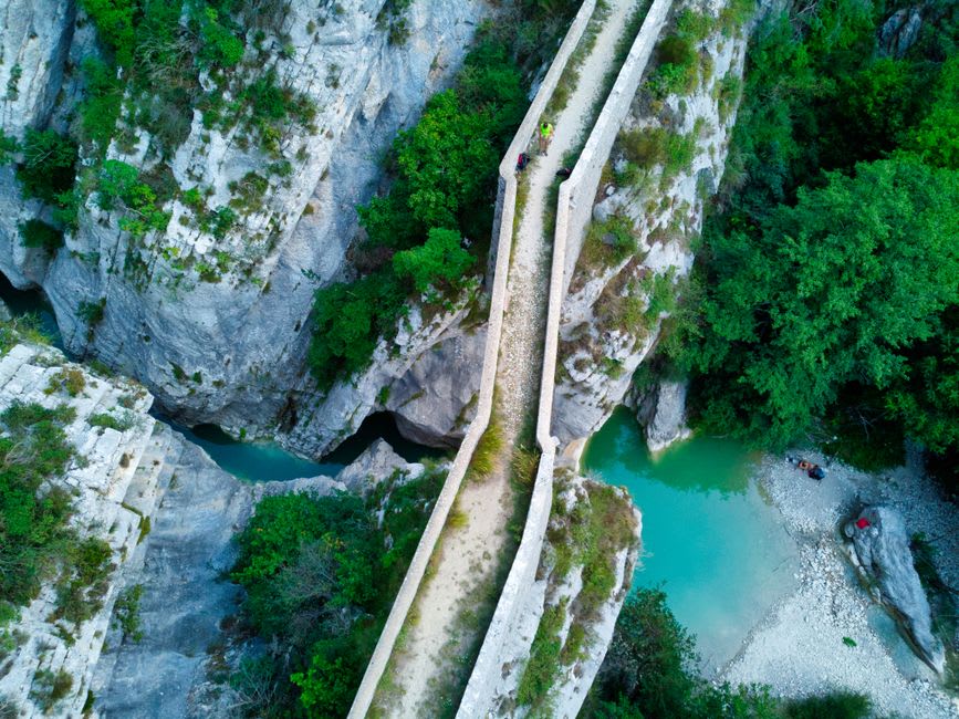 Turquoise meltwater rushing through the narrow marble walls of Marble Canyon beneath a footbridge