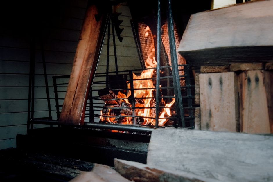 Interior of a reconstructed Norse longhouse with a central hearth fire and turf walls