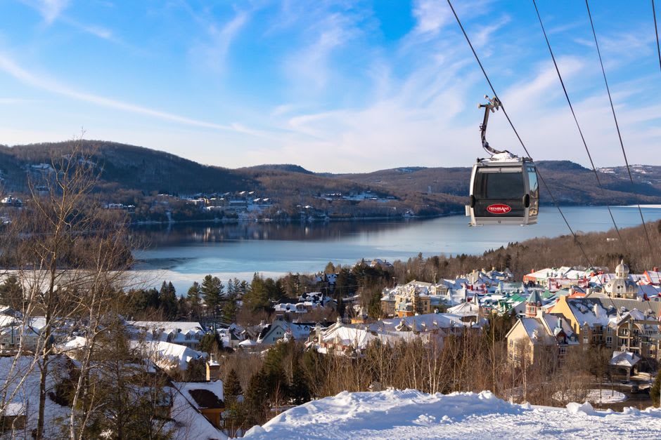 Skier riding a gondola over the colourful village square at Mont-Tremblant