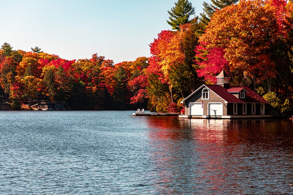 Ornate wooden boathouse with a peaked roof built directly over the water on a Muskoka lake