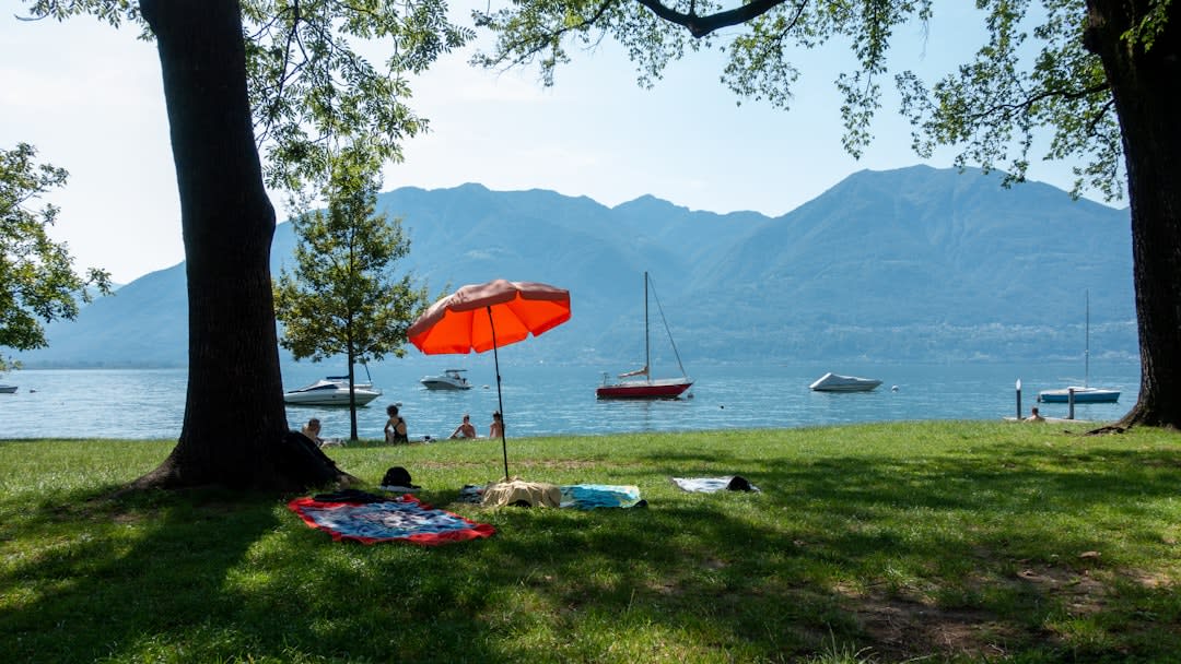 Sunbathers on the sandy shore of Osoyoos Lake with dry hillsides rising behind the turquoise water