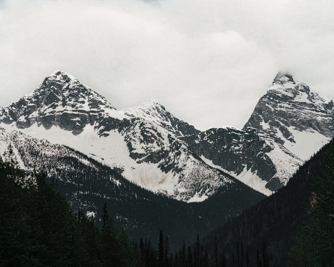 Highway winding through steep, avalanche-scarred mountain terrain in a Rocky Mountain pass