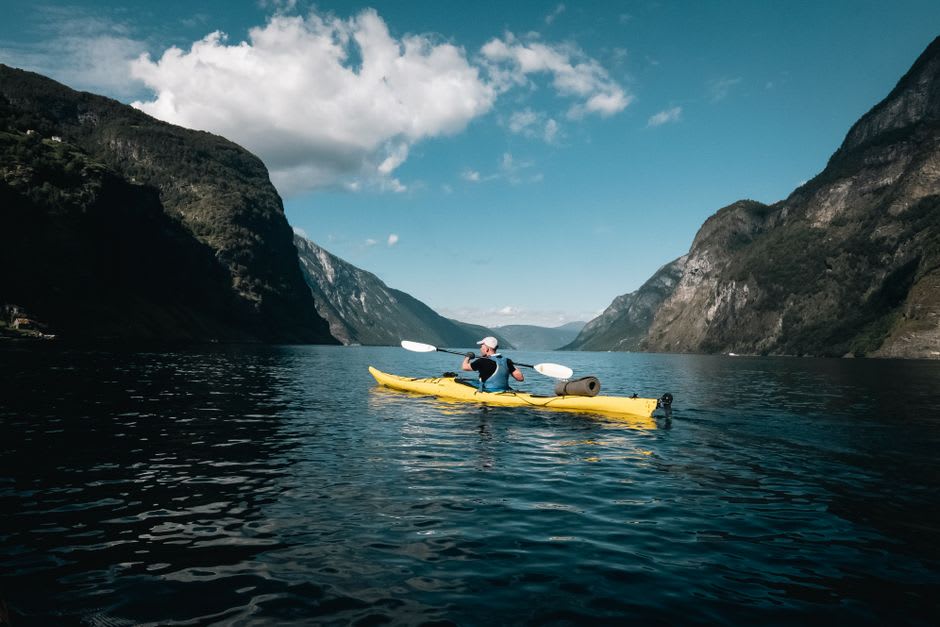 Sea kayaker paddling beneath the towering cliffs of Cap Trinité