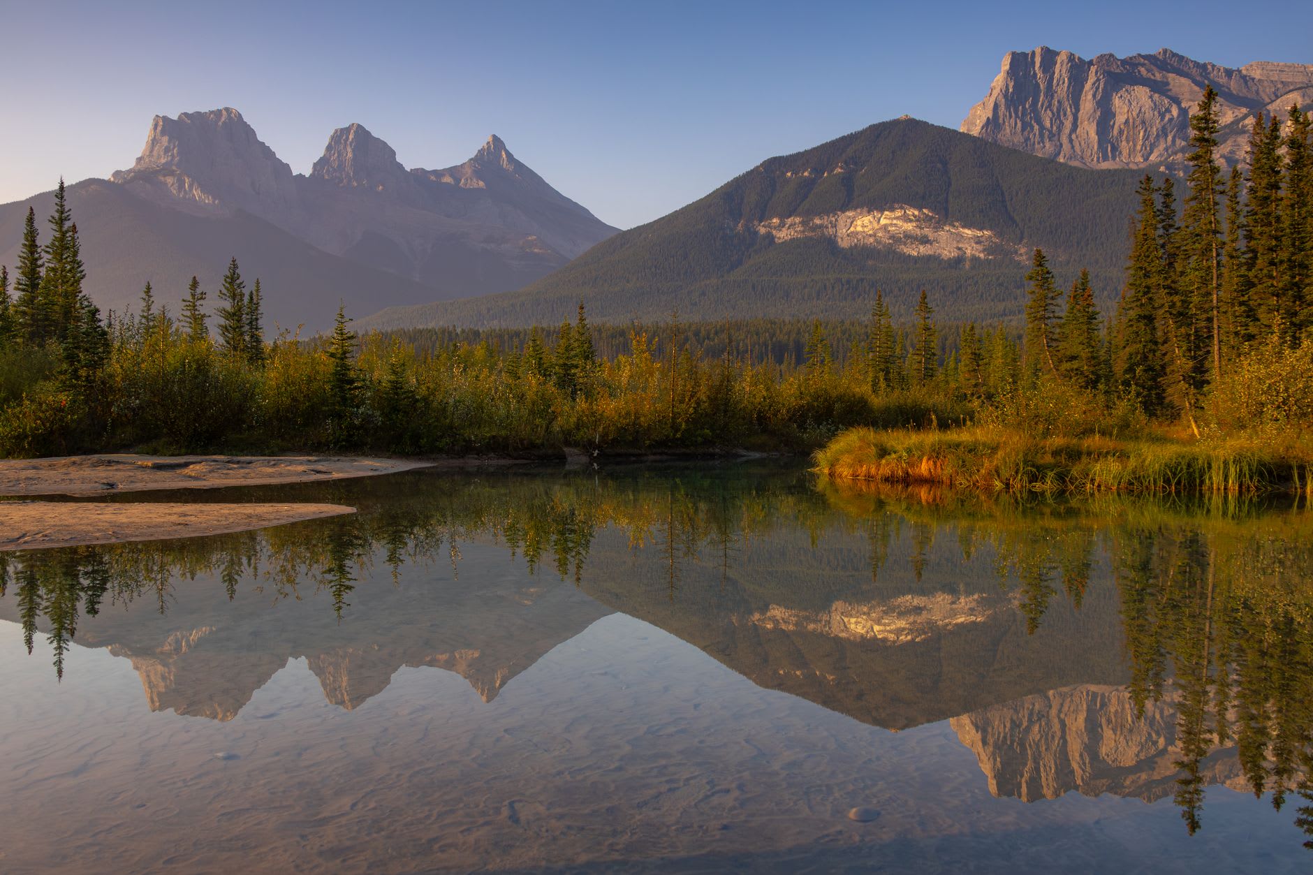 La Calle Principal de Canmore en una mañana brillante con la Cordillera Rundle llenando el cielo detrás de los escaparates