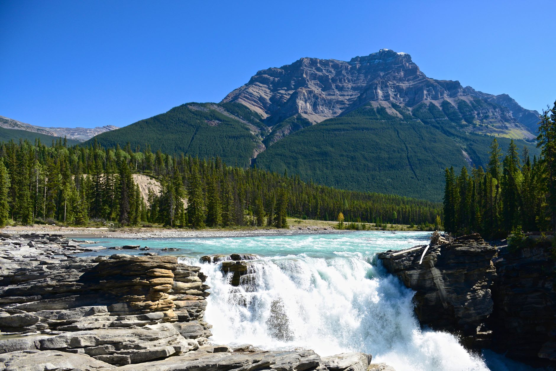 The Lower Falls in Johnston Canyon dropping through a natural limestone portal into a turquoise pool