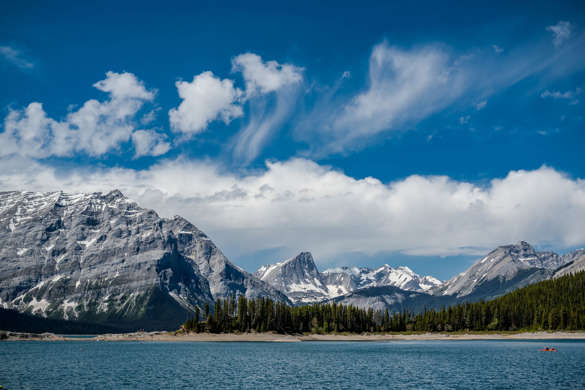 Spirit Island at golden hour, warm light on the spruce trees and the jade lake stretching to the peaks behind