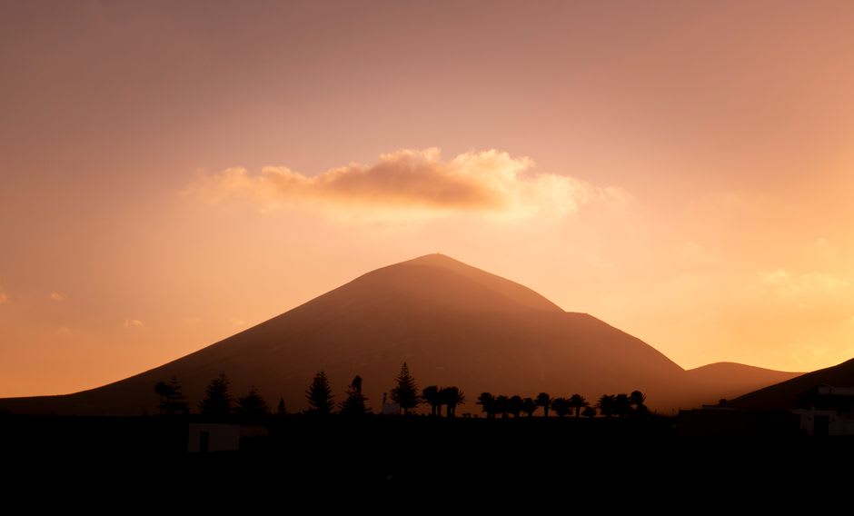 Roque Nublo monolith with Teide volcano visible on the horizon across the strait