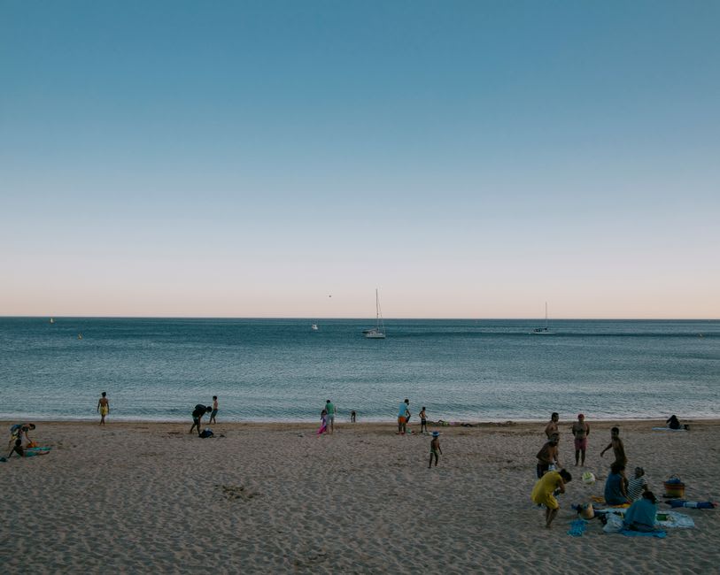 The wide sheltered curve of Fish Hoek beach with families spread along the shore