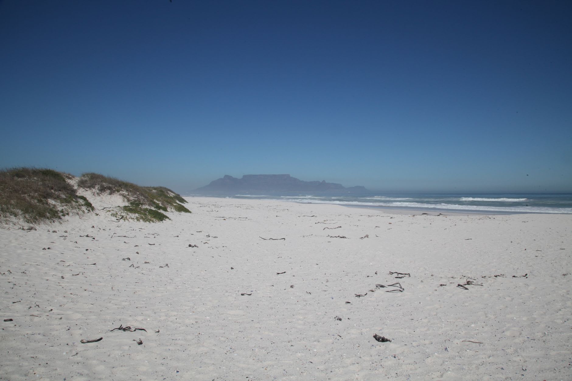 Slangkop Lighthouse rising above the coastal scrub at Kommetjie, the long white arc of Long Beach stretching south behind it
