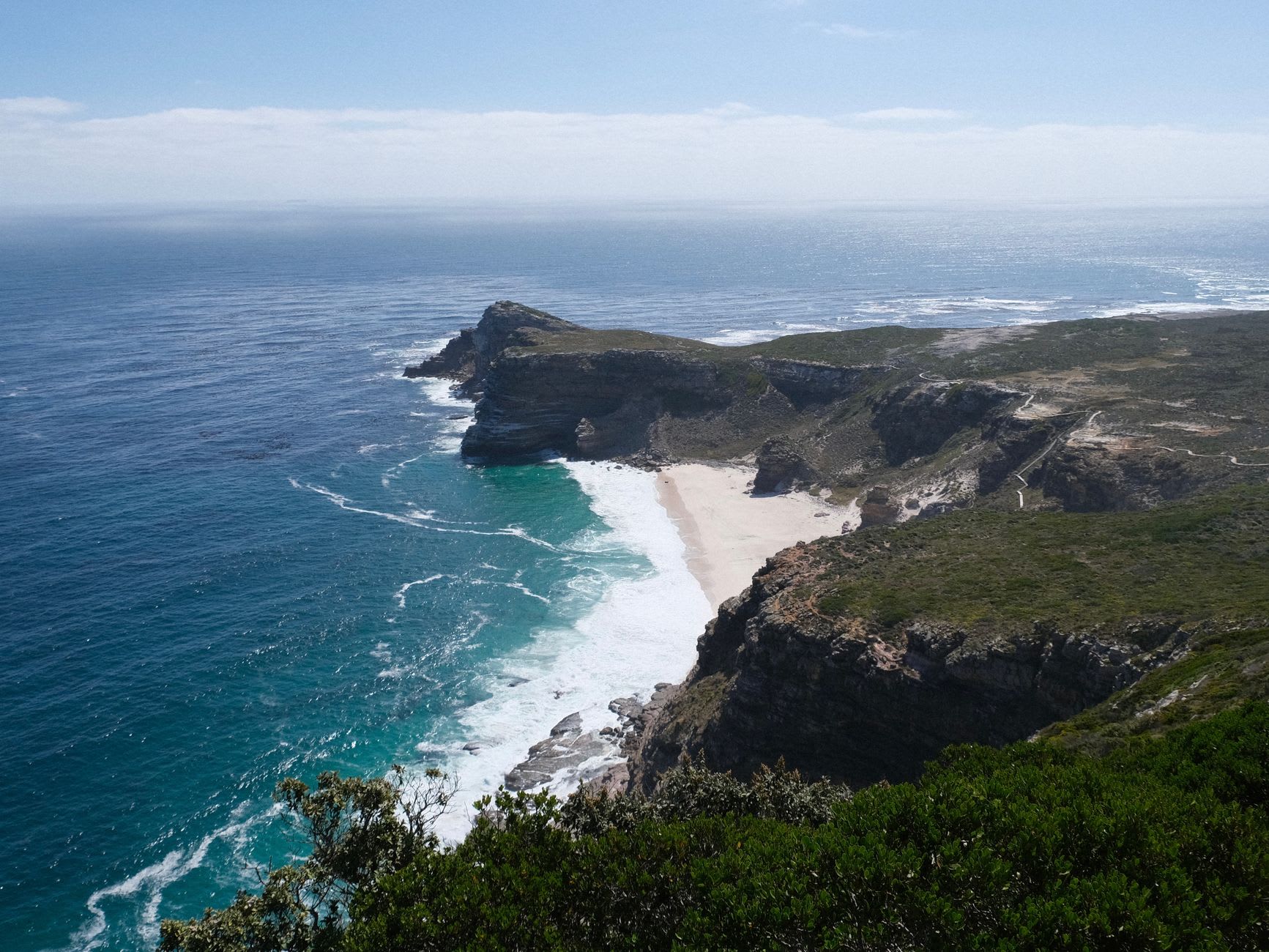 La zone humide de Noordhoek derrière la plage au crépuscule, des flamants roses pataugeant dans une eau peu profonde aux teintes roses