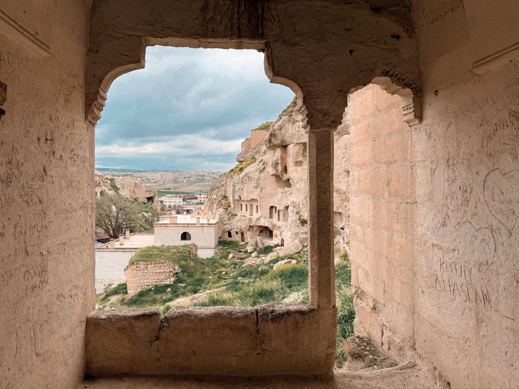 One of Derinkuyu's massive circular millstone doors, rolled back into its alcove beside a carved passage with a narrow corridor beyond