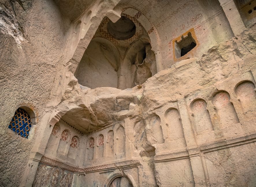 Byzantine rock-cut church frescoes preserved in the cliffside chapels of Soğanlı Valley, faded reds and blues on a carved stone ceiling