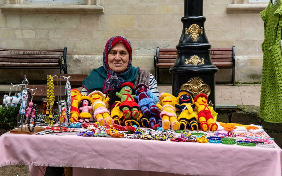 Elderly women selling handmade cloth dolls and knitted socks at folding tables near the entrance to Soğanlı Valley