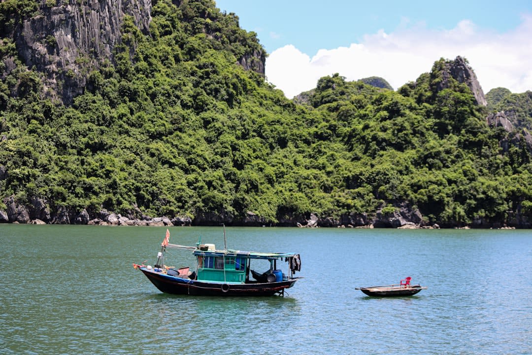 Boat approaching the turquoise cove at Kỳ Co with granite boulders lining the shore