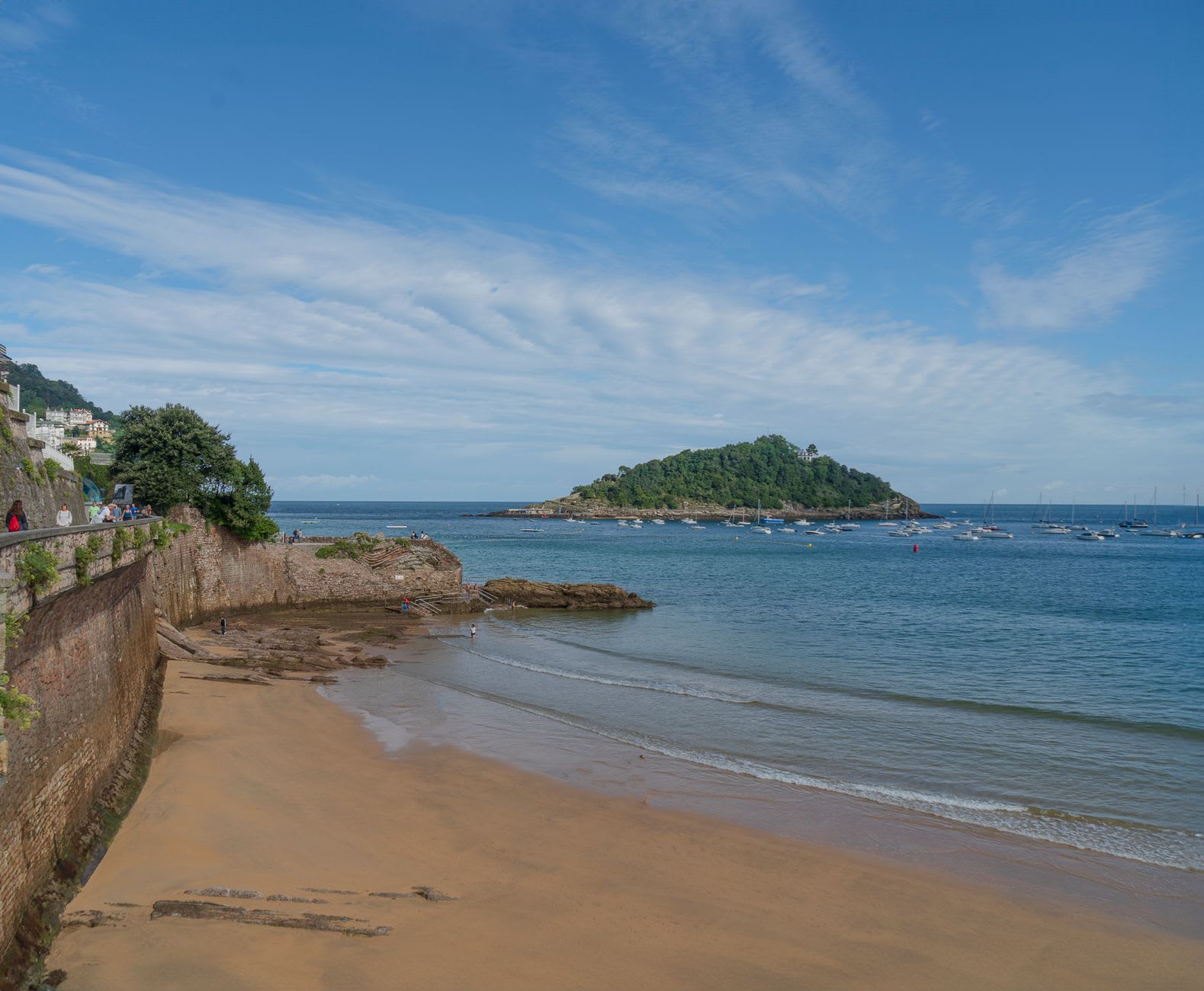 The Norman Fishermen's Chapel at the western end of St. Brelade's Bay with roses against the wall and the beach beyond