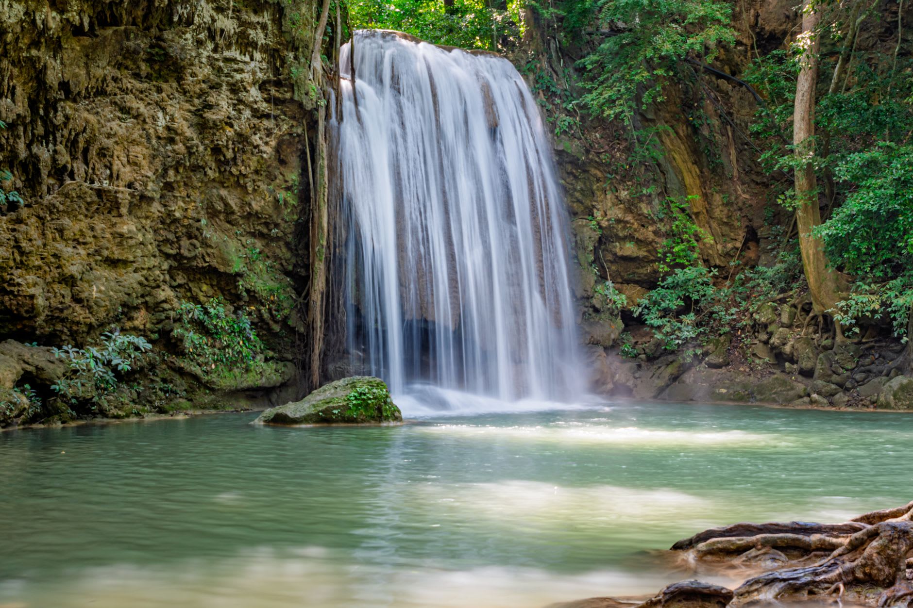 Woman floating in a deep turquoise pool at Agua Azul with jungle reflected in the still water