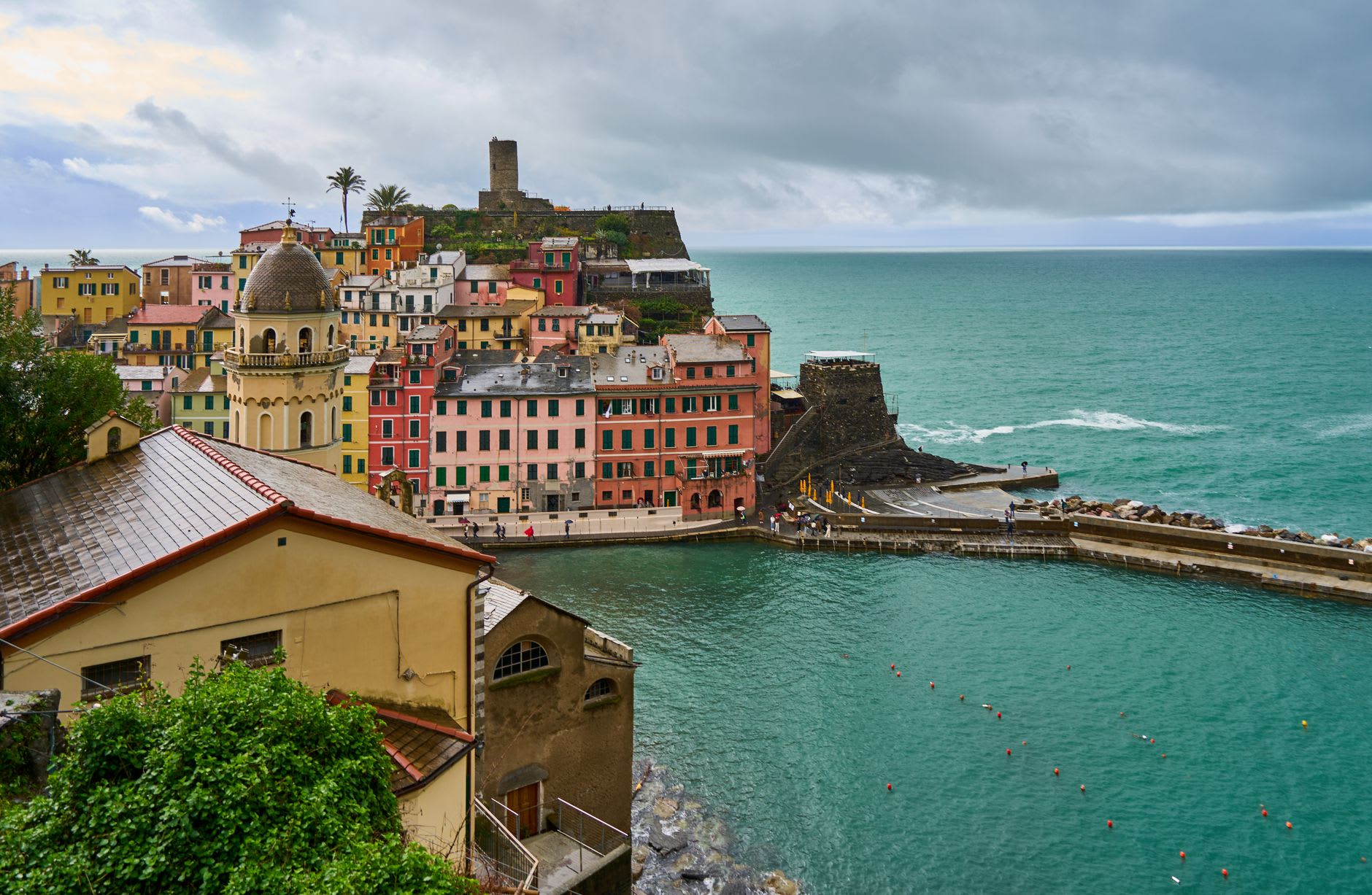Tables du café de la piazza de Vernazza face au port, bateaux de pêche reflétés dans l'eau calme du matin
