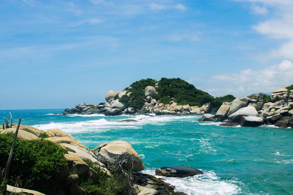 A jungle-fringed Caribbean beach with boulders and turquoise water