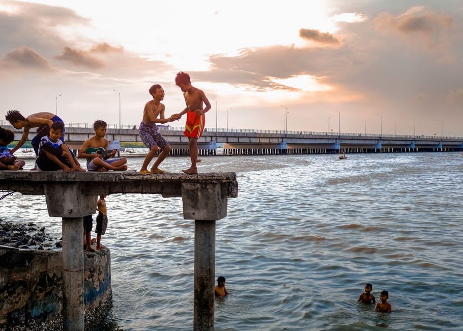 Local children playing in the shallow lagoon waters near a small jetty at Titikaveka