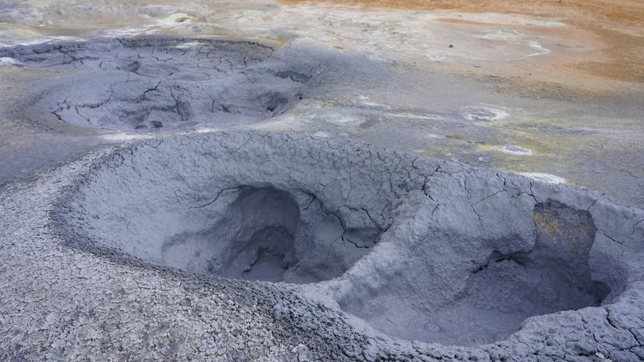 Volcanic mud pots bubbling with steam in a geothermal landscape