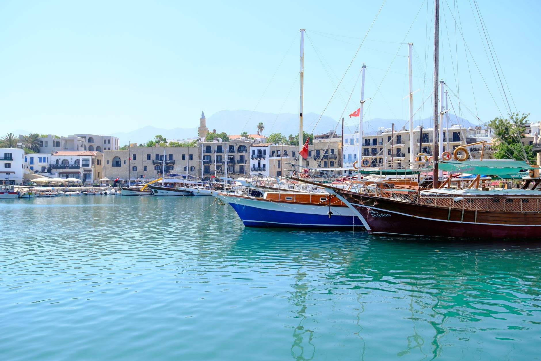 Kyrenia castle wall meeting the sea at sunset, orange stone and turquoise water with small boats at rest in the harbour