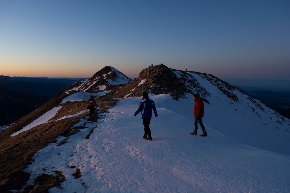 Trekkers on the Sandakphu ridge trail at dawn with snow peaks in the distance