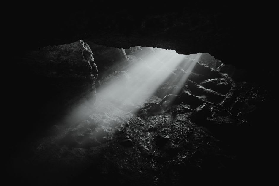 Sunlight filtering down through a narrow crack in the ceiling of the Flour Cave, illuminating fine white dust suspended in the air