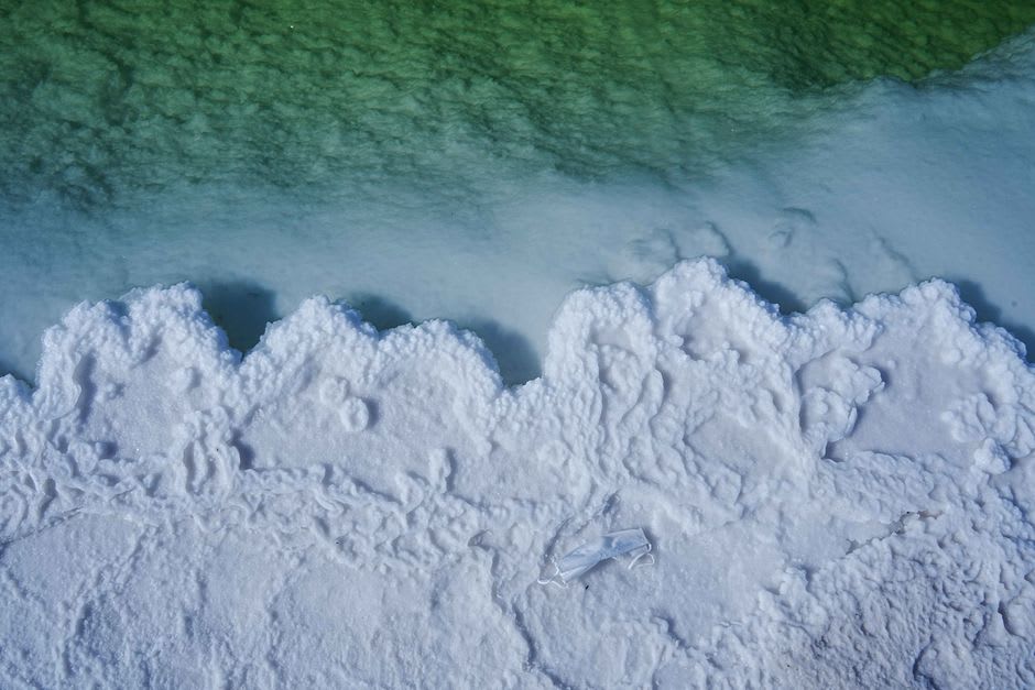 La surface du mont Sodome parsemée de cristaux de sel captant la lumière rasante du soleil, craquelée et striée comme des vagues figées